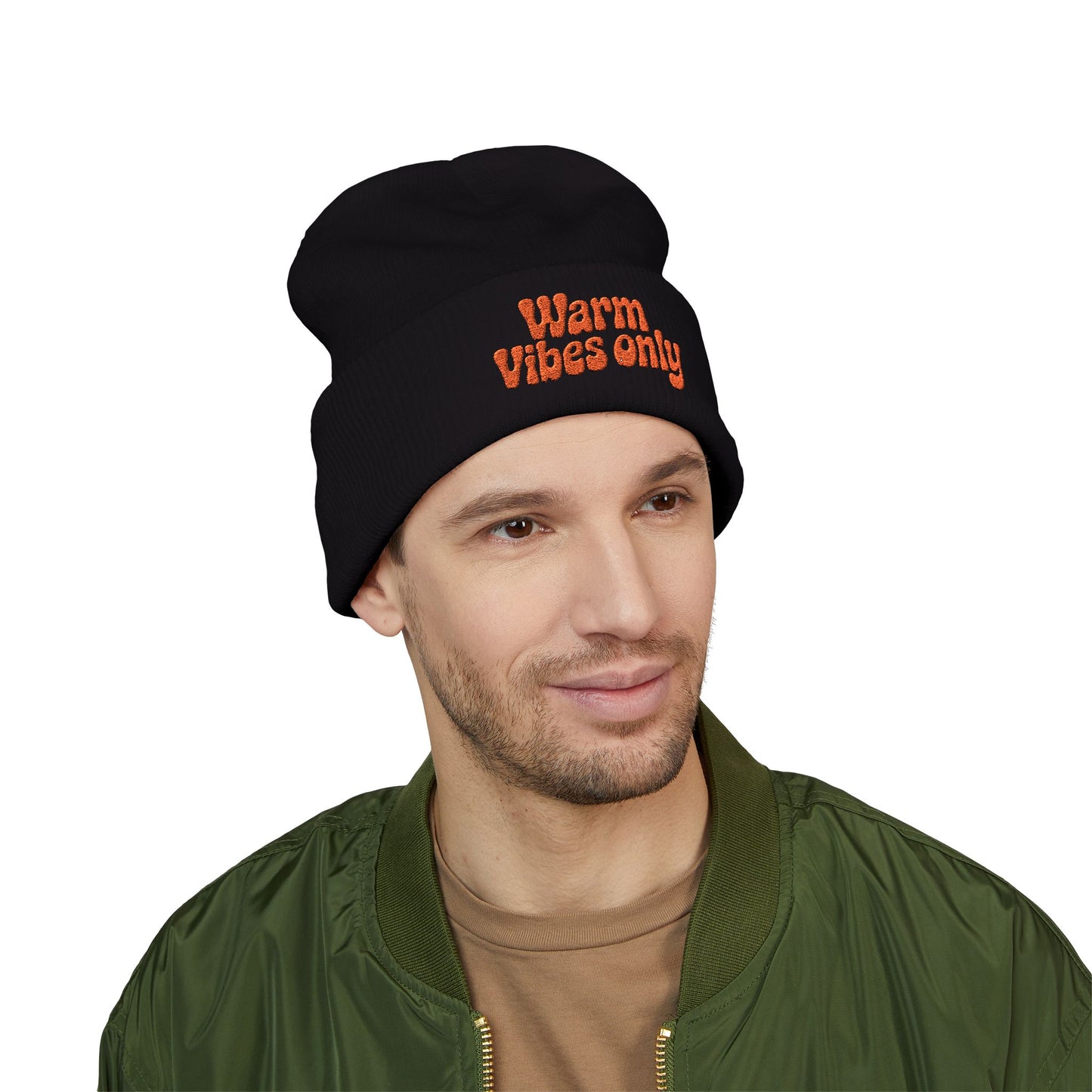 Man wearing a black beanie with 'Warm Vibes only' text on a white background. Close-up of cheerful orange “Warm vibes only” embroidery on winter knit hat.