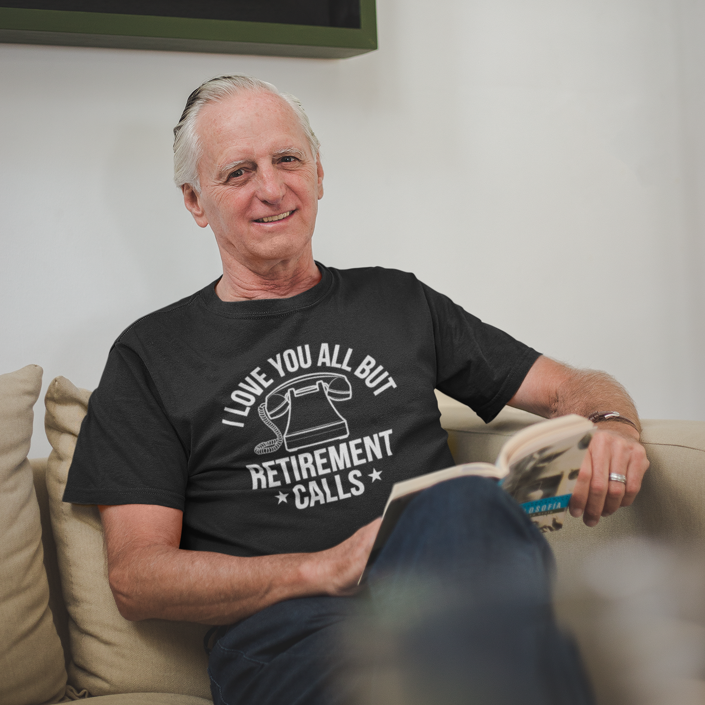 “Retired man sitting on couch wearing black ‘I Love You All But Retirement Calls’ shirt, relaxed pose, front view.”