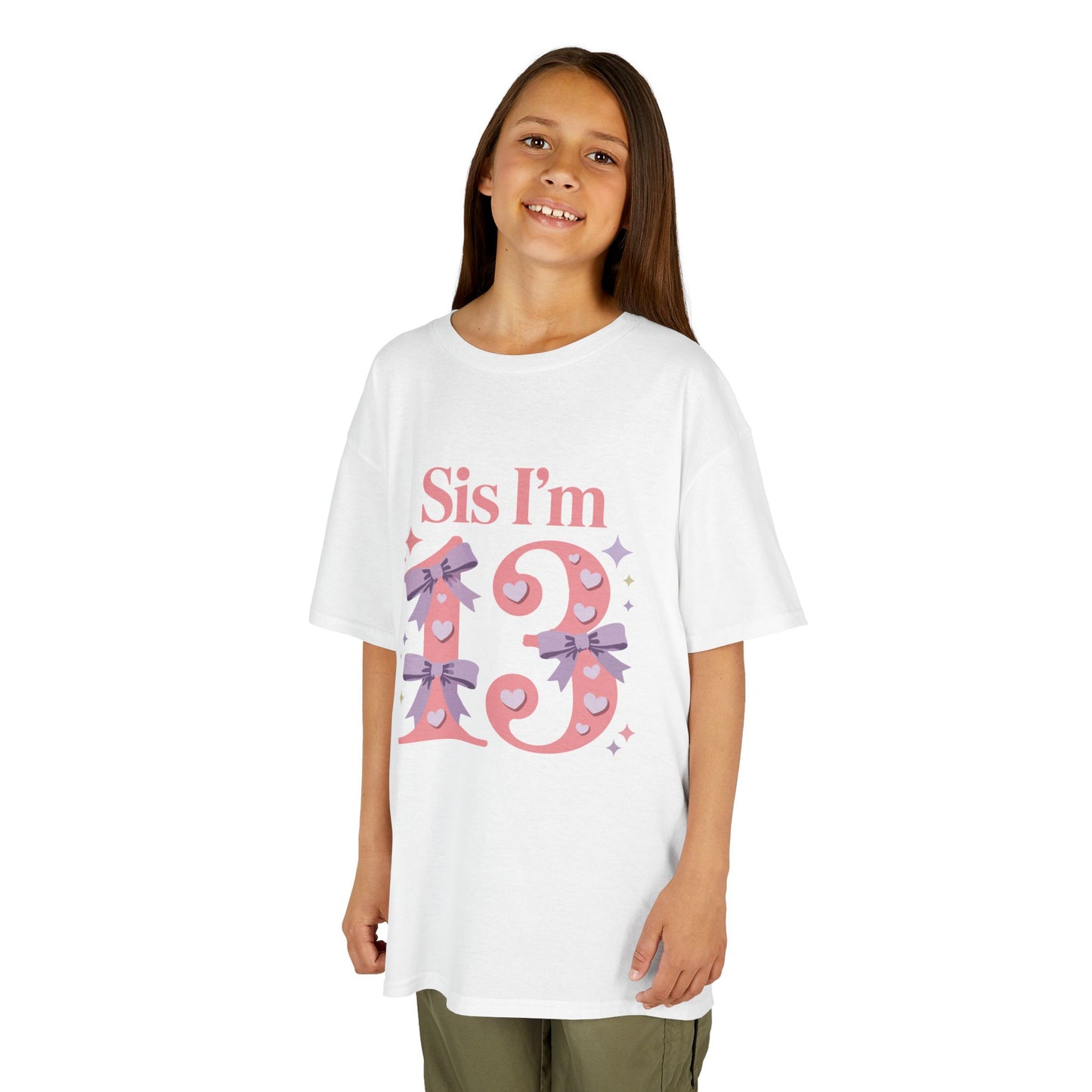 young girl wearing white t‑shirt with pink “Sis I’m 13” design featuring hearts, lilac bows, and sparkles, flat front view.