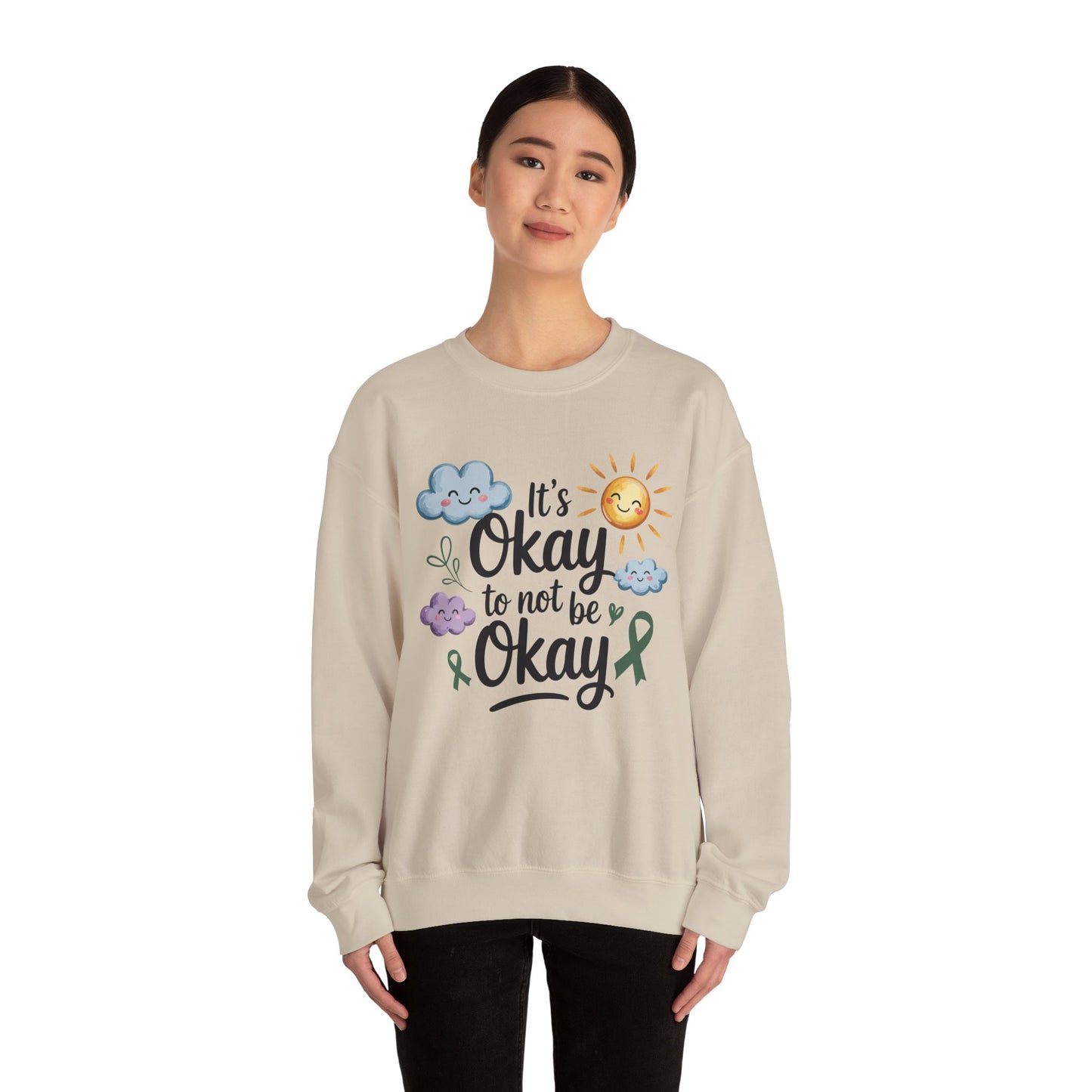TEEZOCA it’s okay to not be okay sweatshirt with cute clouds and sun Person wearing a beige sweatshirt with a motivational quote and sun/cloud design on a white background