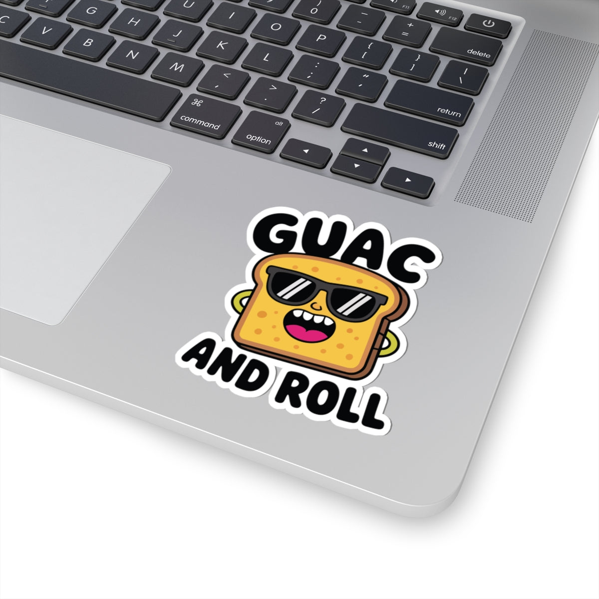 Laptop with a sticker of a cartoon guacamole container wearing sunglasses and text 'GUAC AND ROLL' on a white background. TEEZOCA