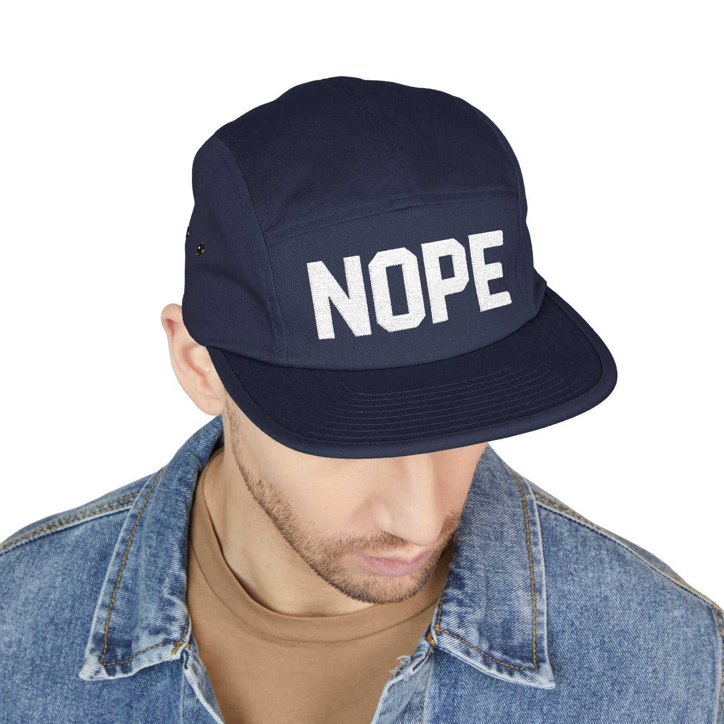 Navy cap with 'NOPE' text worn by a person on a white background. NOPE bold minimal typography embroidery design on cap. TEEZOCA