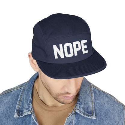 Navy cap with 'NOPE' text worn by a person on a white background. NOPE bold minimal typography embroidery design on cap. TEEZOCA
