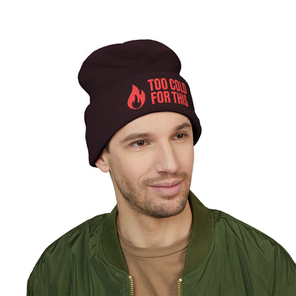 Man wearing a black beanie with red text on a white background. Black beanie with red flame graphic and text 'Too Cold For This' on a white background. Cozy winter hat with humorous cold-weather message and flame graphic
