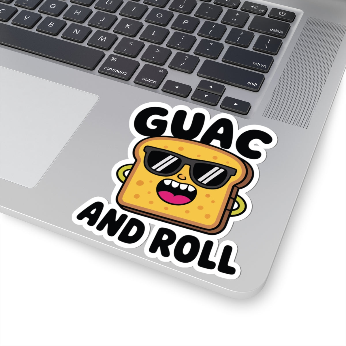 Laptop with a sticker of a cartoon avocado toast wearing sunglasses and text 'GUAC AND ROLL'. TEEZOCA