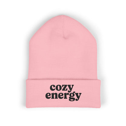 Pink beanie with 'cozy energy' text on a white background