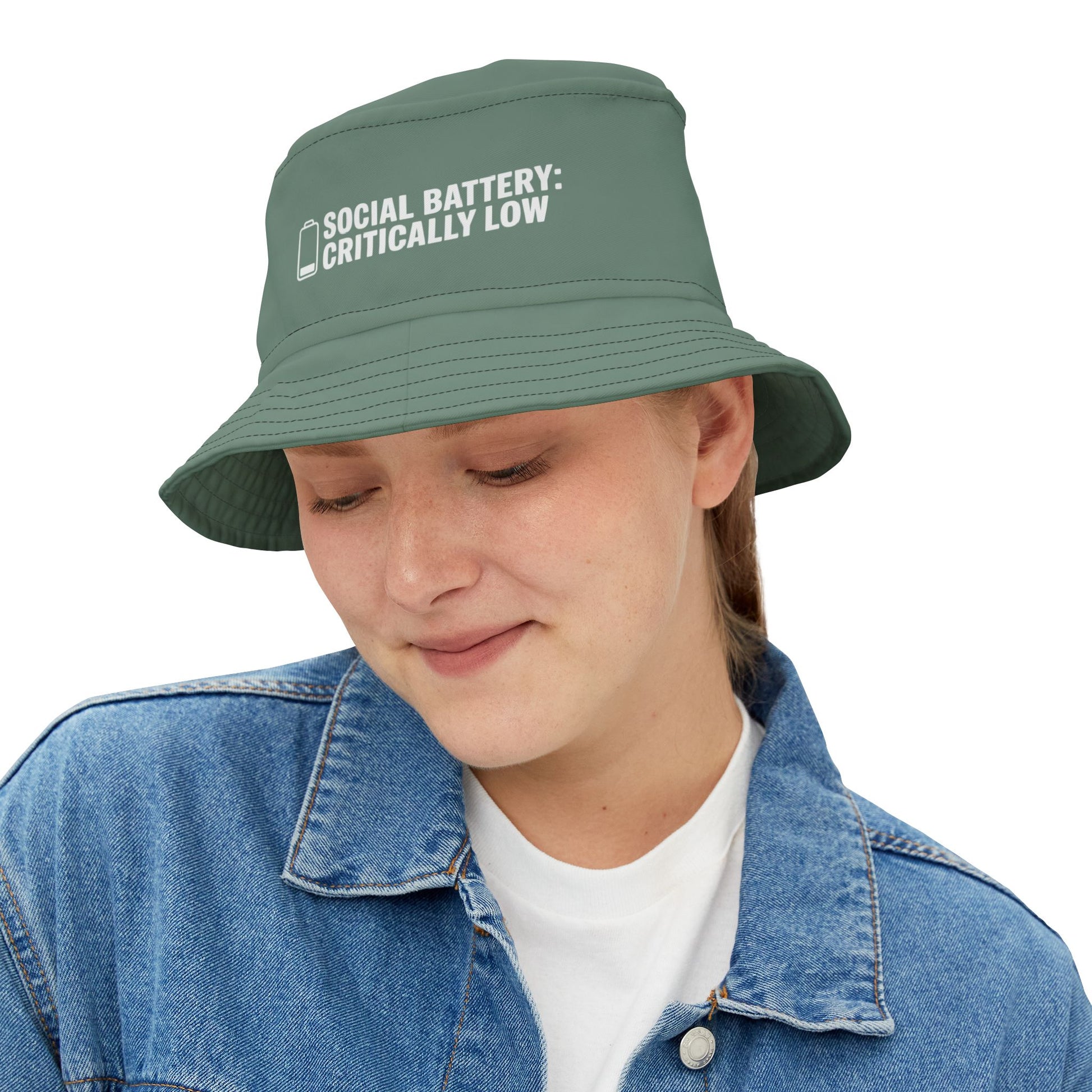 Green bucket hat with funnt text 'Social Battery: Critically Low' on a white background. TEEZOCA