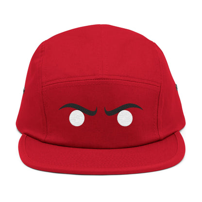 Red cap with cartoonish face design on a white background. Modern streetwear angry eyes icon in high-contrast style. TEEZOCA
