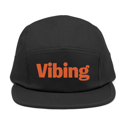 Black cap with 'Vibing' text in orange on a white background. Bold red Vibing typography stitched on casual cap. TEEZOCA

