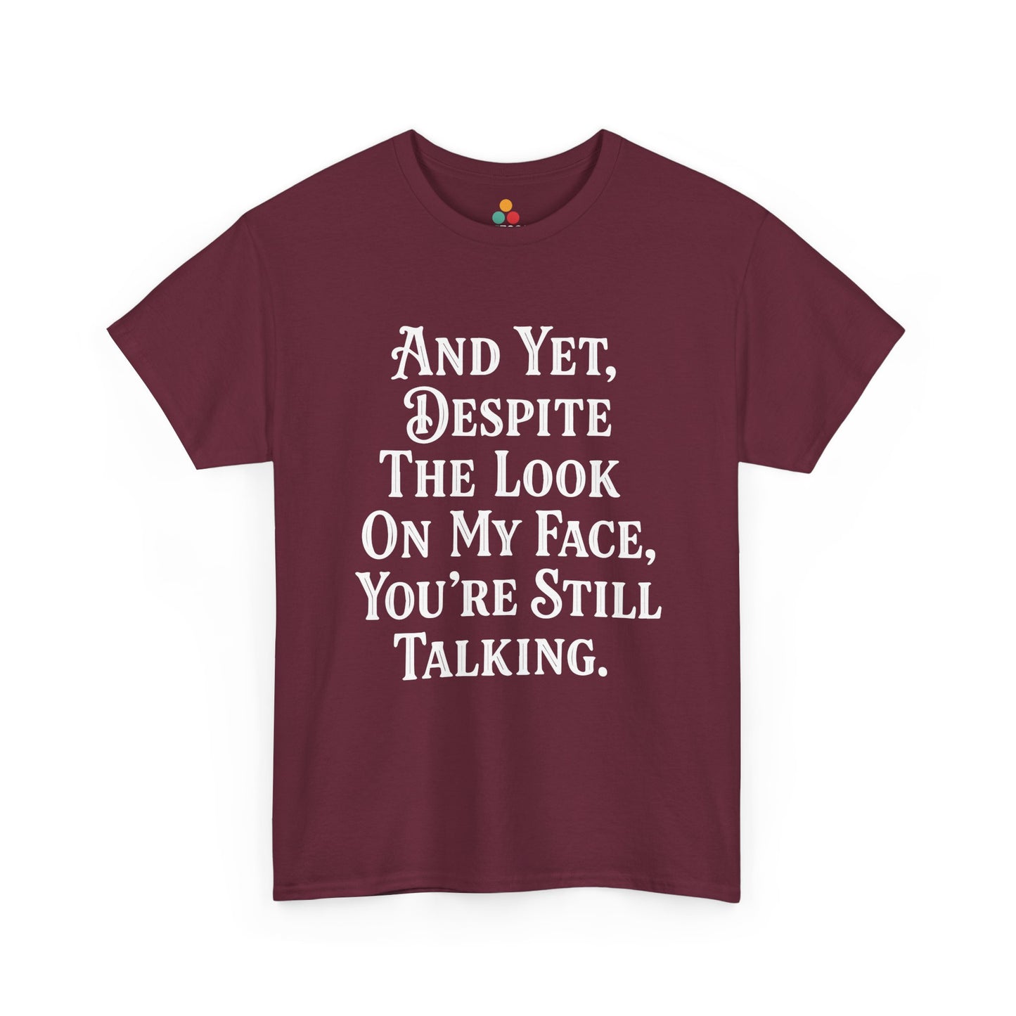 “Teezoca And Yet Despite the Look on My Face You’re Still Talking shirt, funny sarcasm quote in white text, maroon tee, flat front display.”

