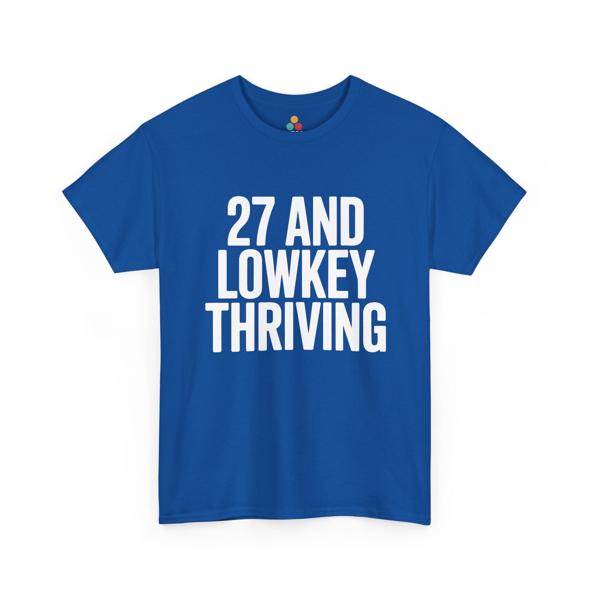 Blue t-shirt with white text '27 AND LOWKEY THRIVING' on a white background