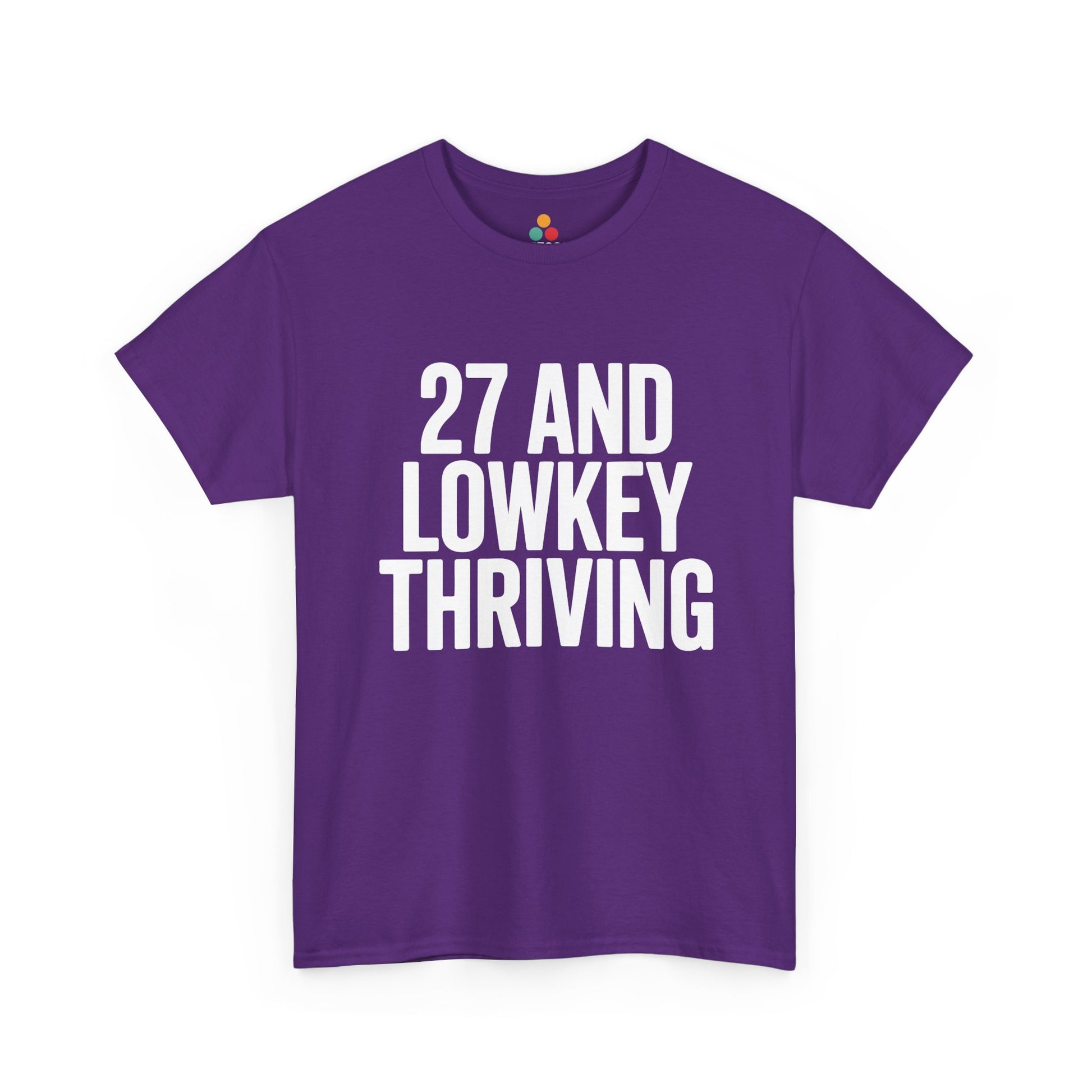 Purple t-shirt with white text '27 AND LOWKEY THRIVING' on a white background