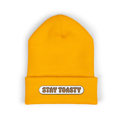 Yellow beanie with 'Stay Toasty' label on a white background