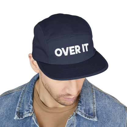 Navy cap with 'OVER IT' text worn by a person on a white background. OVER IT embroidered text design displayed on clean white typography. TEEZOCA