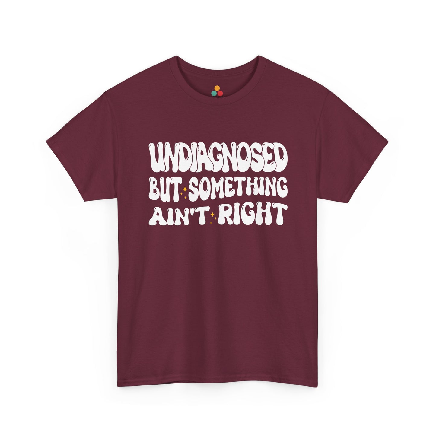 “Teezoca Undiagnosed But Something Ain’t Right shirt, white wavy text and sparkles, maroon tee, flat front display.”​

