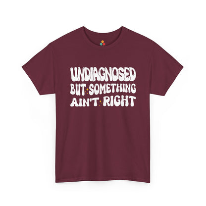 “Teezoca Undiagnosed But Something Ain’t Right shirt, white wavy text and sparkles, maroon tee, flat front display.”​

