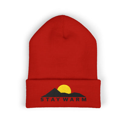 Red beanie with mountain and sun design and 'Stay Warm' text on a white background