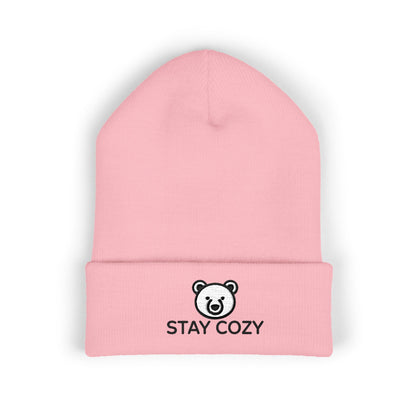 Pink beanie with 'Stay Cozy' text and bear logo on a white background