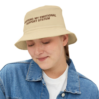 Beige bucket hat with funny text 'CAFFEINE: MY EMOTIONAL SUPPORT SYSTEM' on a white background. TEEZOCA