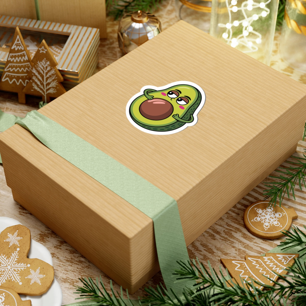 Gift box with a cartoon avocado sticker on a festive background with cookies and decorations. TEEZOCA