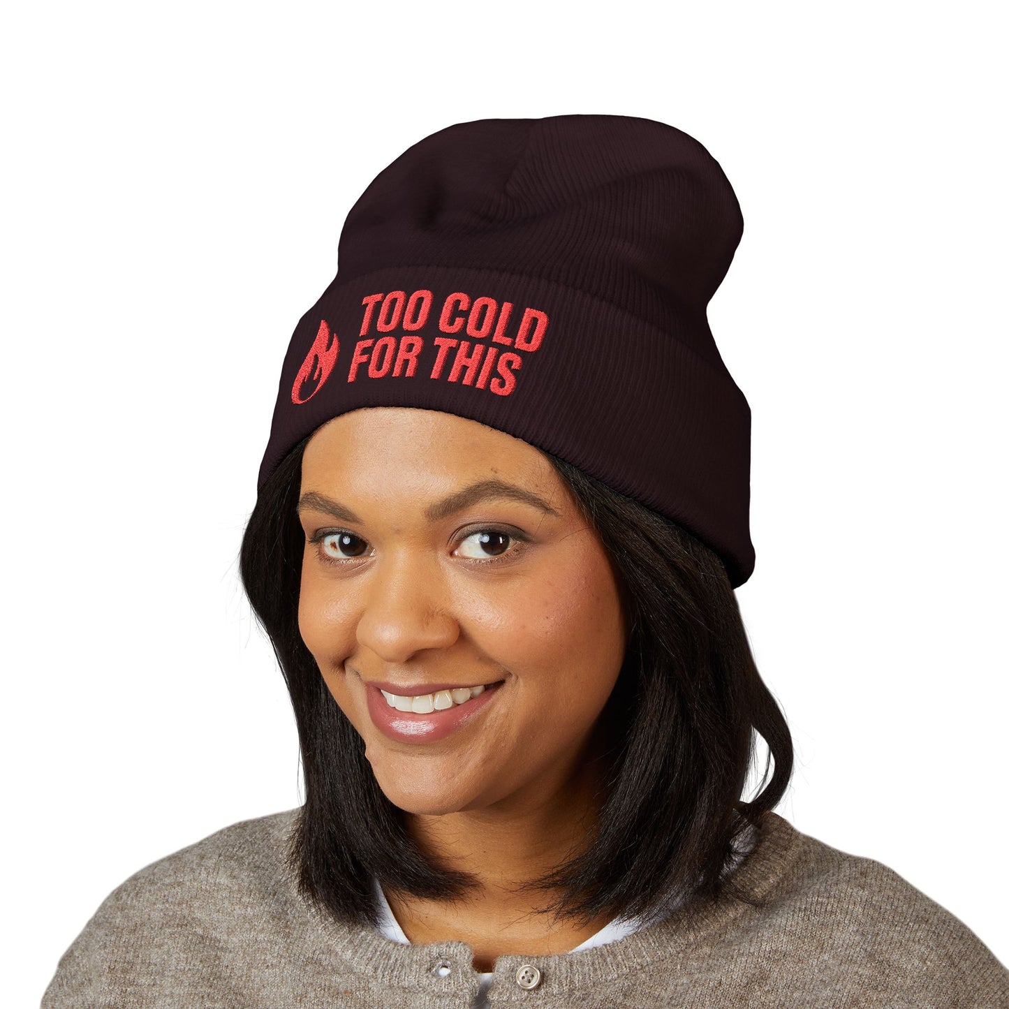 Person wearing a black beanie with red text on a white background. Funny slogan winter beanie reading “Too Cold For This” in red stitching