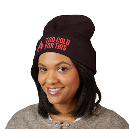 Person wearing a black beanie with red text on a white background. Funny slogan winter beanie reading “Too Cold For This” in red stitching