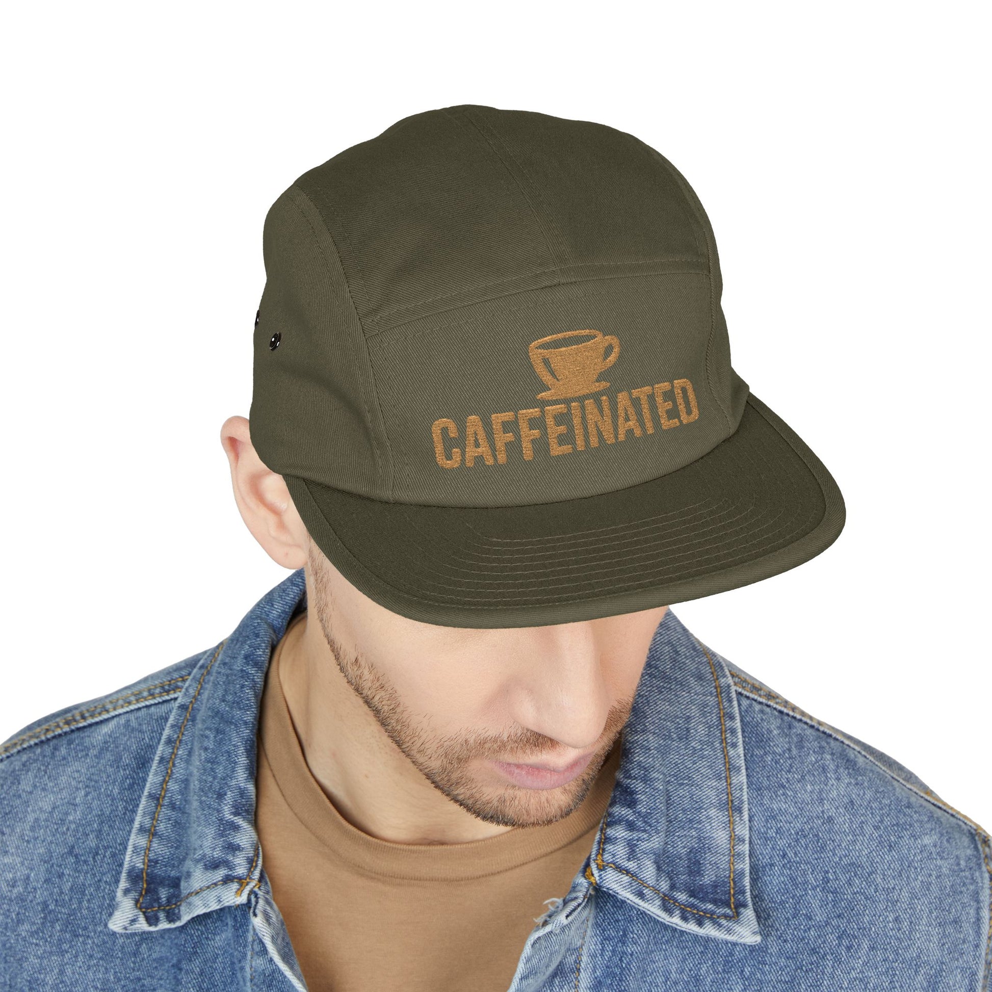 Green cap with 'CAFFEINATED' text worn by a person on a white background. Caffeinated coffee cup icon embroidered design on five-panel cap. TEEZOCA