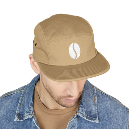 Man wearing a brown cap with a coffee bean icon on a white background. Embroidered coffee bean icon on beige 5-panel cap. TEEZOCA