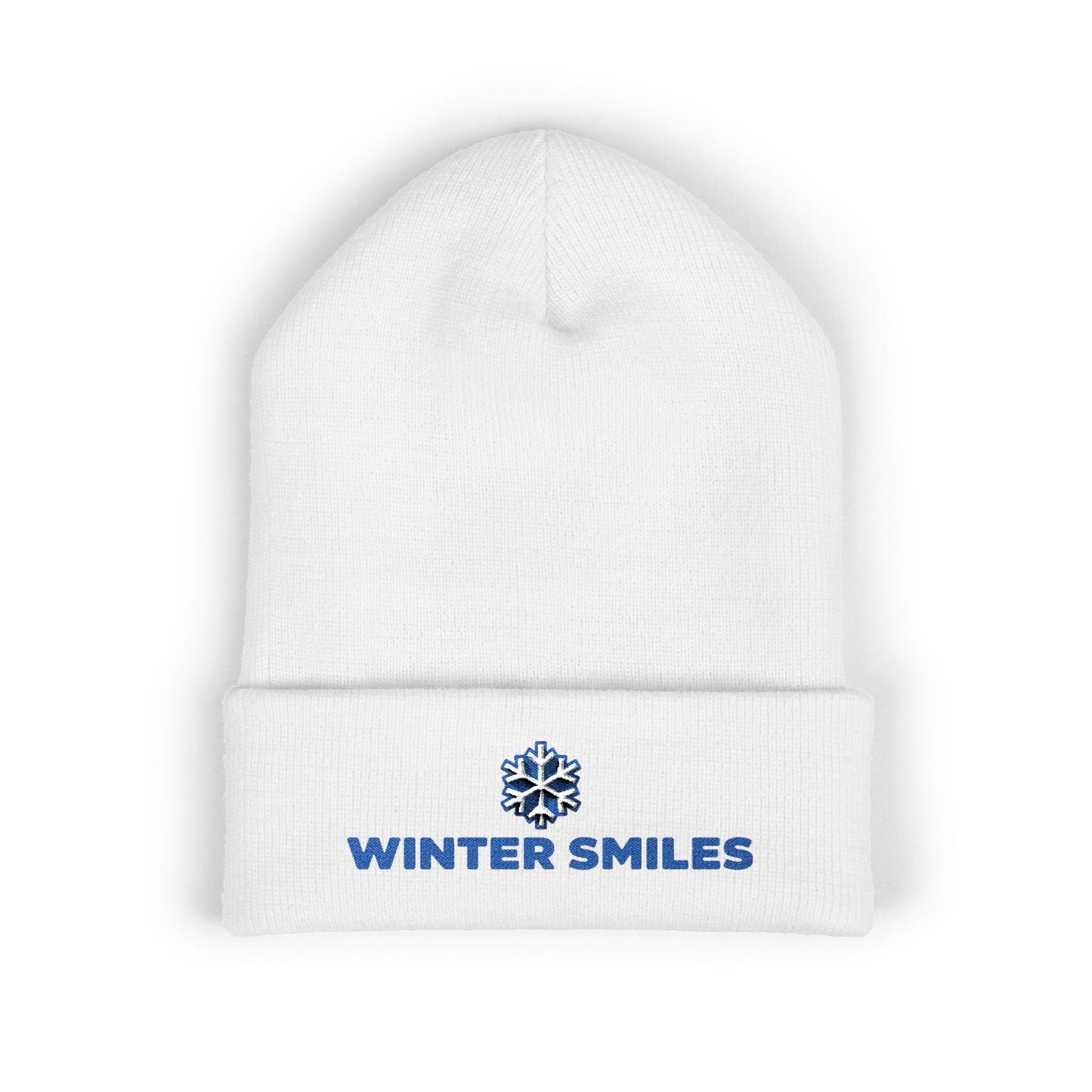 White beanie with 'Winter Smiles' logo on a white background. Blue embroidered “Winter Smiles” snowflake design on cuffed winter beanie