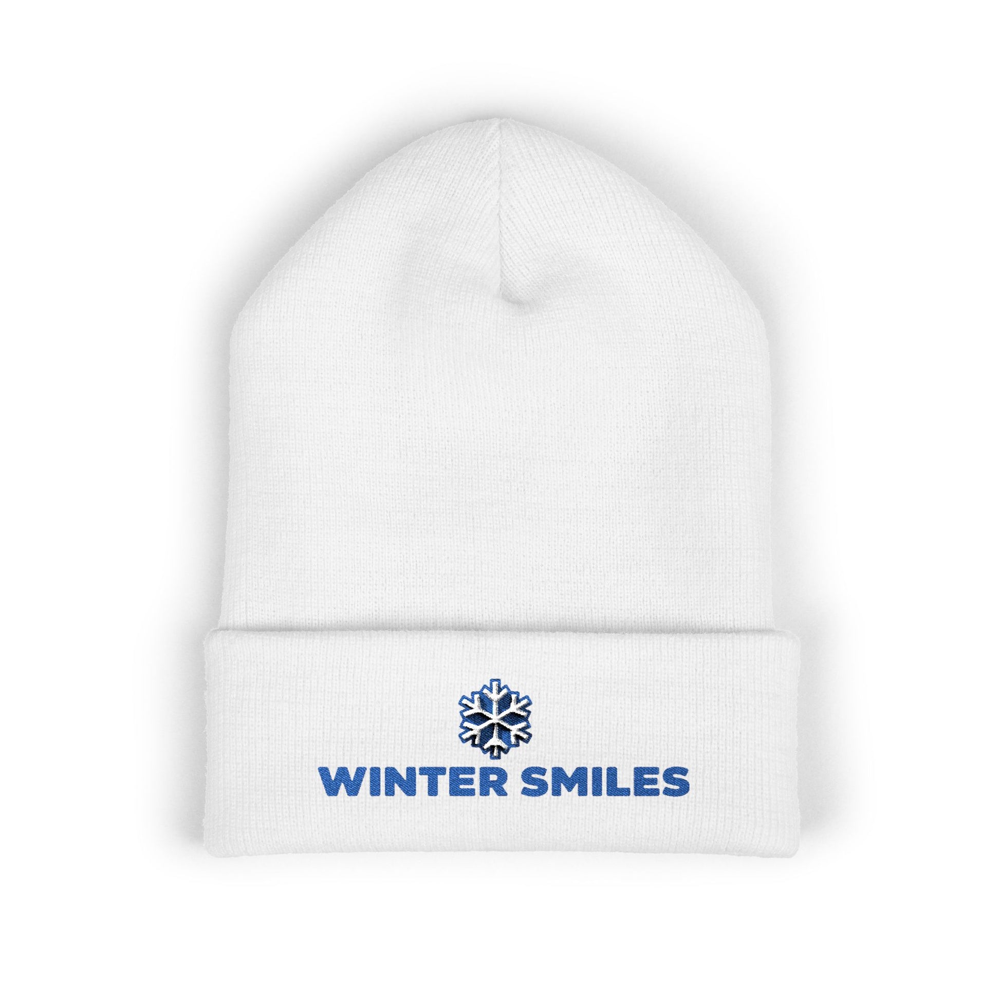 White beanie with 'Winter Smiles' logo on a white background. Blue embroidered “Winter Smiles” snowflake design on cuffed winter beanie