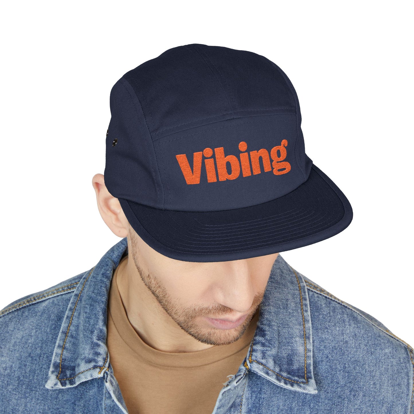 Navy cap with 'Vibing' text worn by a person on a white background. Modern Vibing embroidery design for lifestyle fashion. TEEZOCA