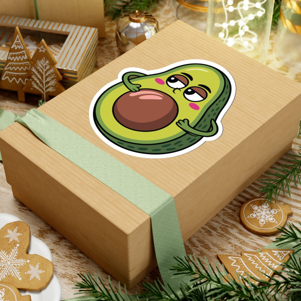 Gift box with a cartoon avocado sticker on a festive background with cookies and decorations. TEEZOCA