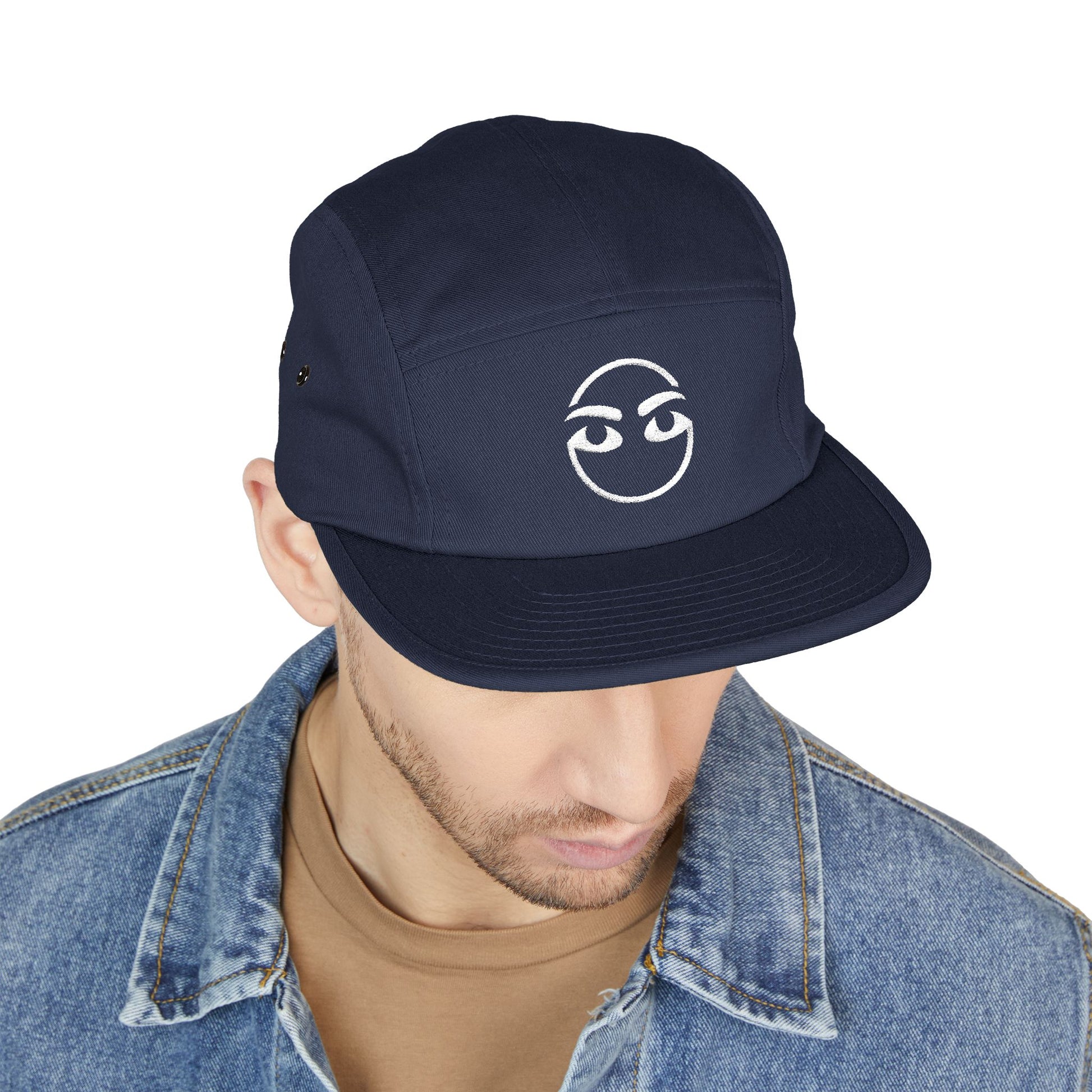Navy blue cap with a white logo worn by a person on a white background. Modern streetwear raised-brow emoji-style embroidery icon. TEEZOCA