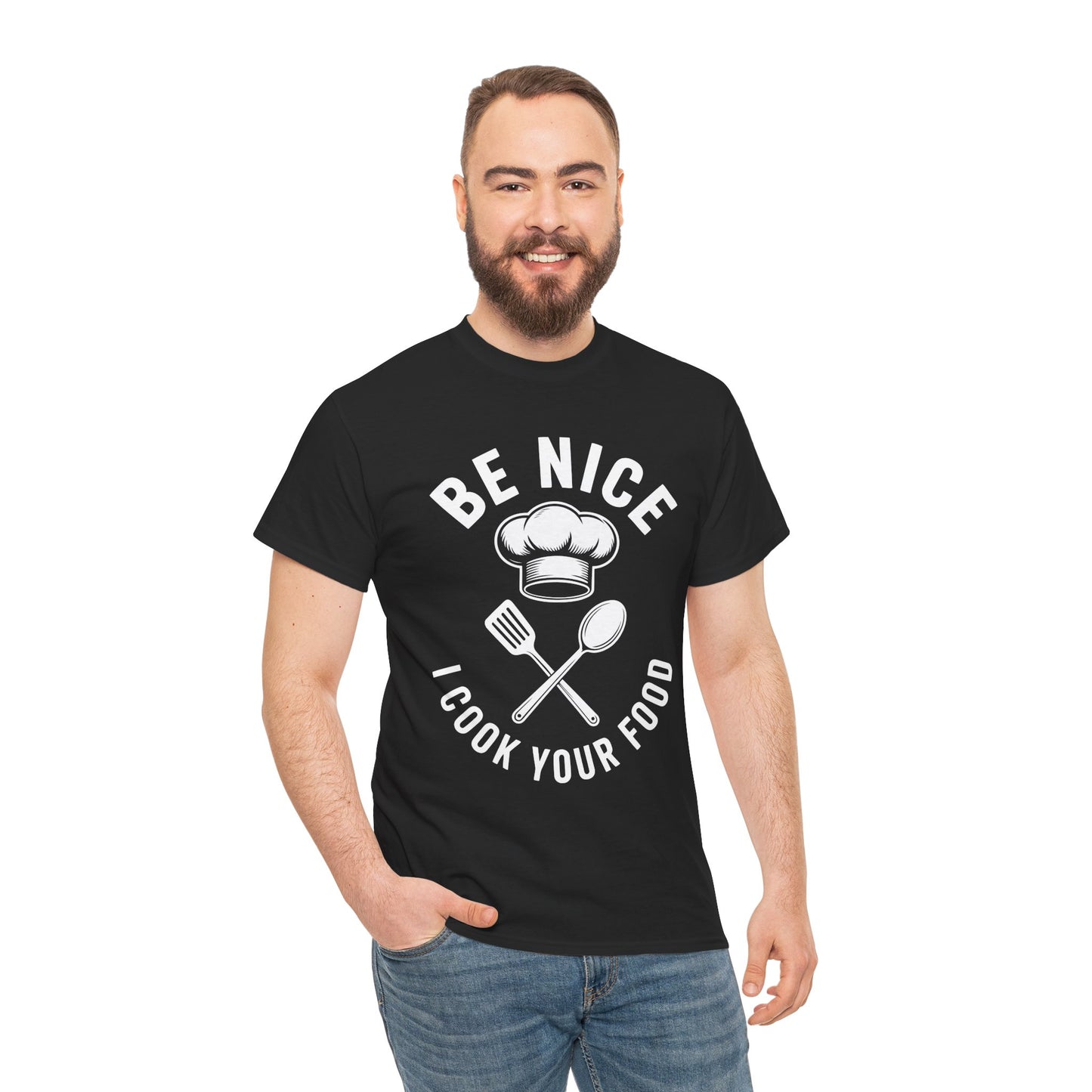 “Male model wearing Teezoca Be Nice I Cook Your Food t-shirt, chef hat and utensils kitchen graphic, black unisex tee, front.”


