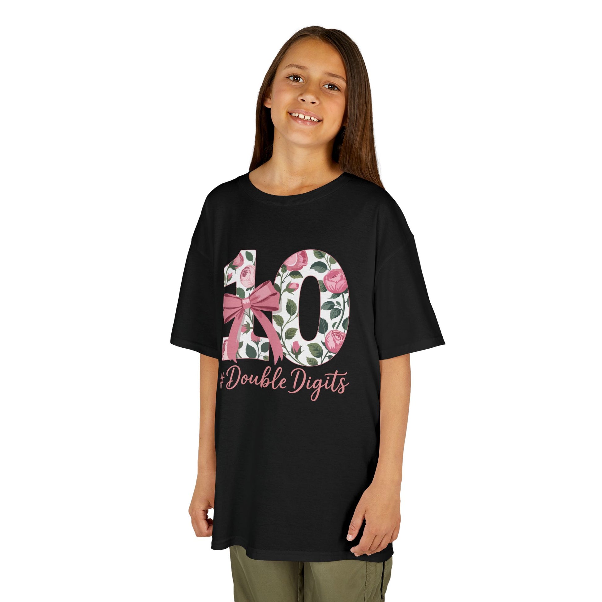 “Girl wearing black 10th birthday floral ‘#DoubleDigits’ shirt with rose‑filled 10 and pink bow, front view.”


