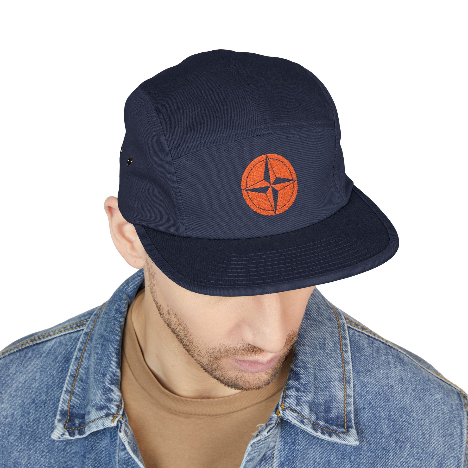 Navy cap with orange logo worn by a person on a white background. minimalist compass star icon embroidered design for 5-panel cap by TEEZOCA