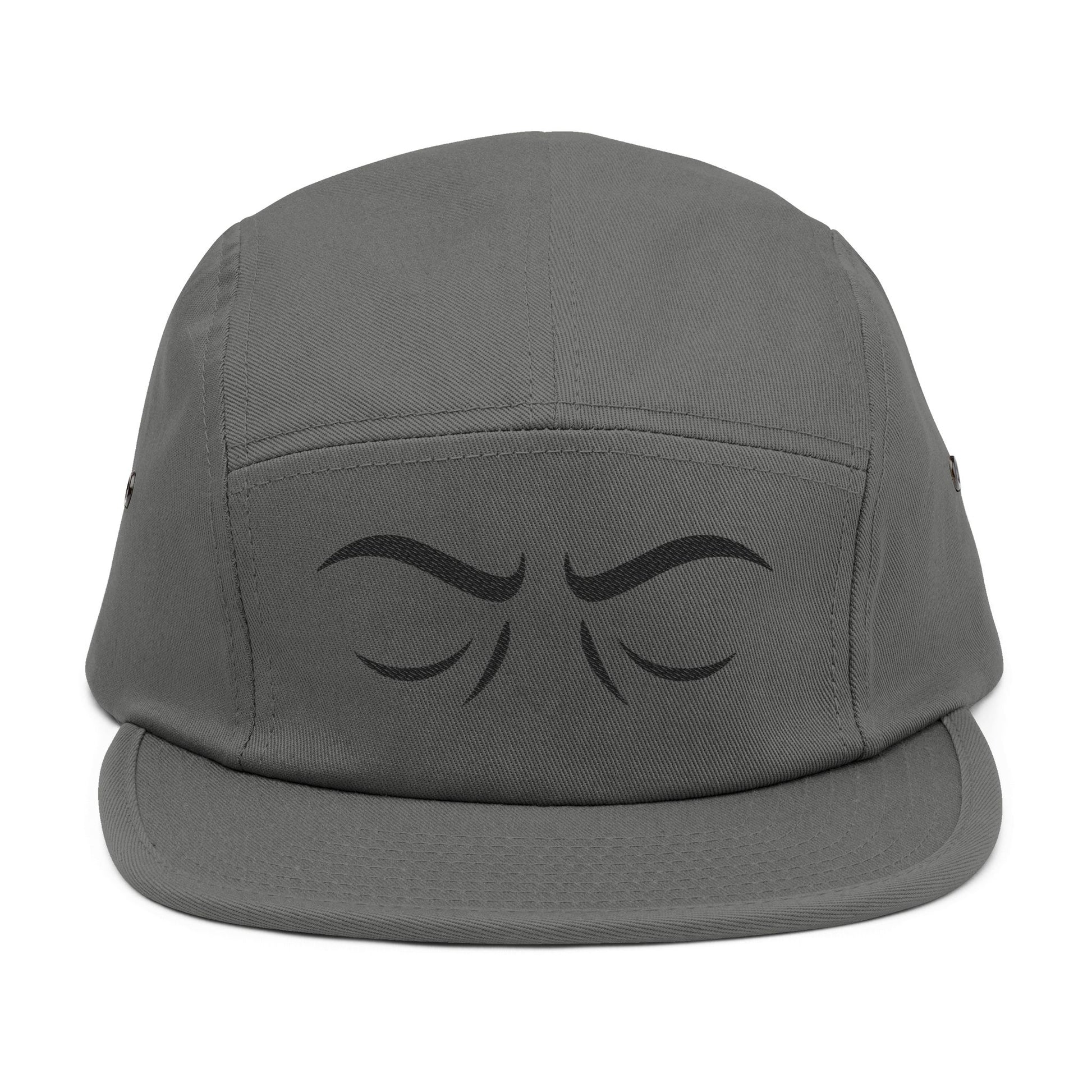 Gray cap with black eye design on a white background. Arched eyebrow expression graphic for embroidery. TEEZOCA