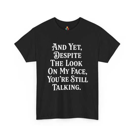 “Teezoca And Yet Despite the Look on My Face You’re Still Talking shirt, bold white serif text, black tee, front view.”

