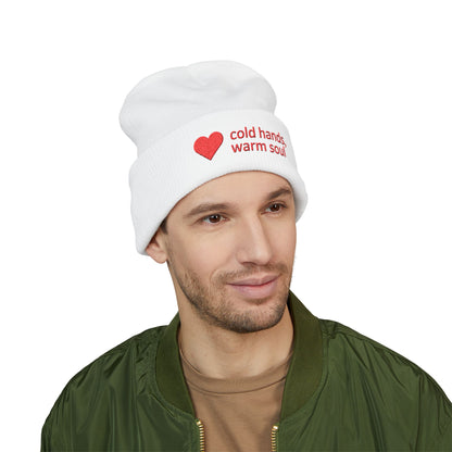 Man wearing a white beanie with text and a heart symbol on a white background. “Cold Hands Warm Soul” embroidered beanie with red heart on cuffed winter knit hat