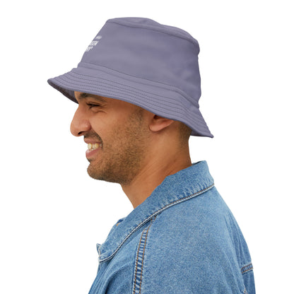 Purple bucket hat with white funny text 'Currently Vibing Between MEH and WHY' on a white background. TEEZOCA