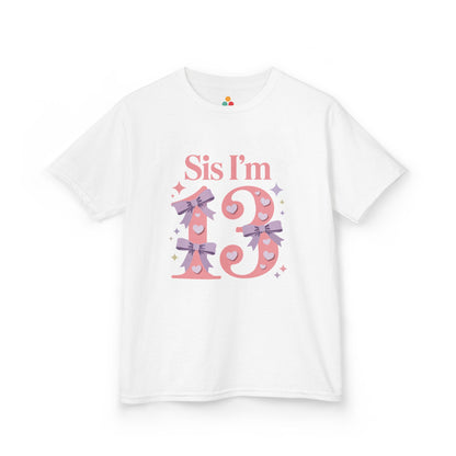 White t‑shirt with pink “Sis I’m 13” design featuring hearts, lilac bows, and sparkles, flat front view.