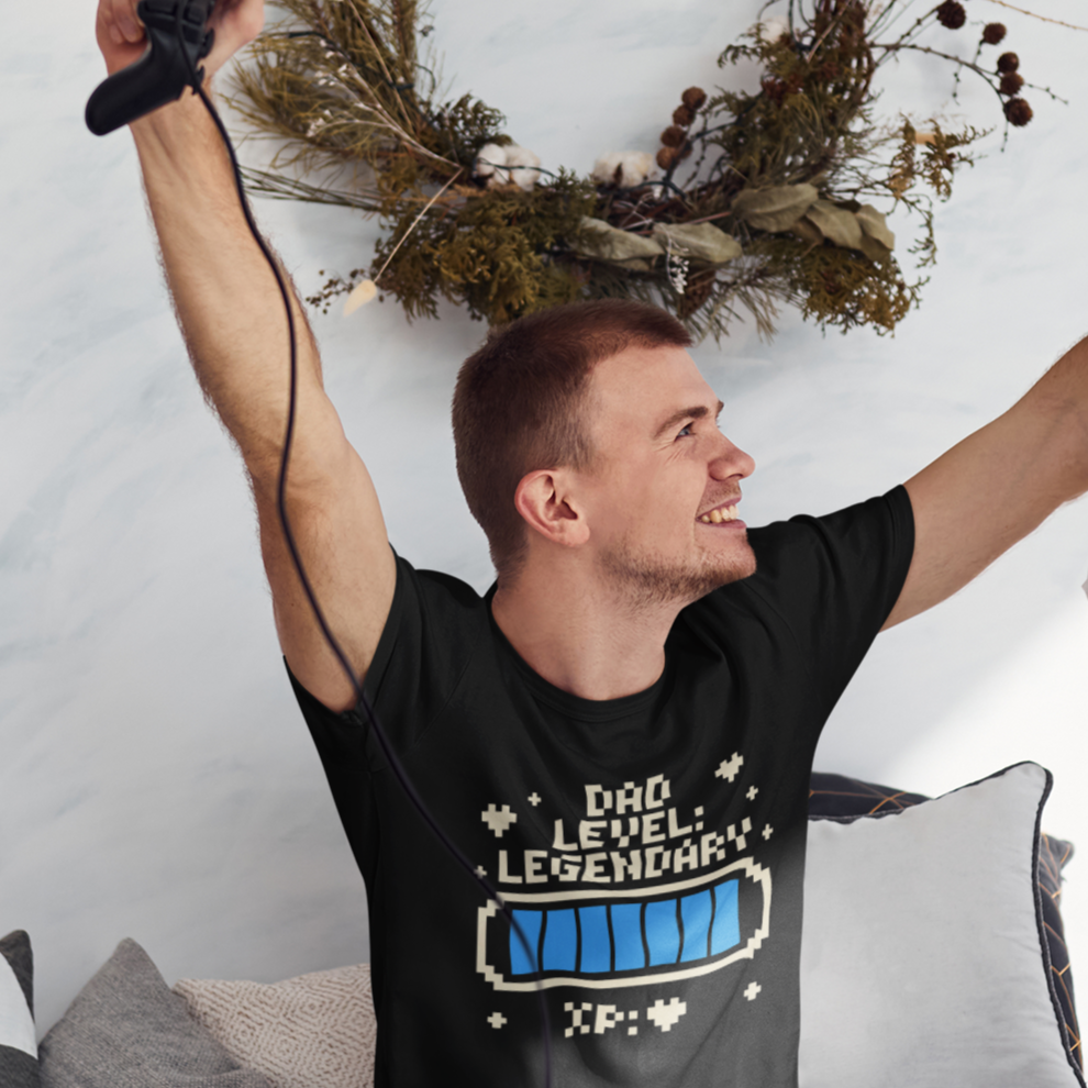 Smiling dad jumping in a TEEZOCA “Dad Level Legendary” gamer tee in a lifestyle photo.
