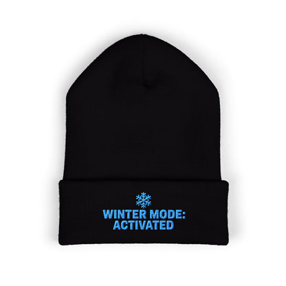 Black beanie with blue text 'Winter Mode: Activated' on a white background. Cuffed winter hat with light-blue snowflake and seasonal slogan