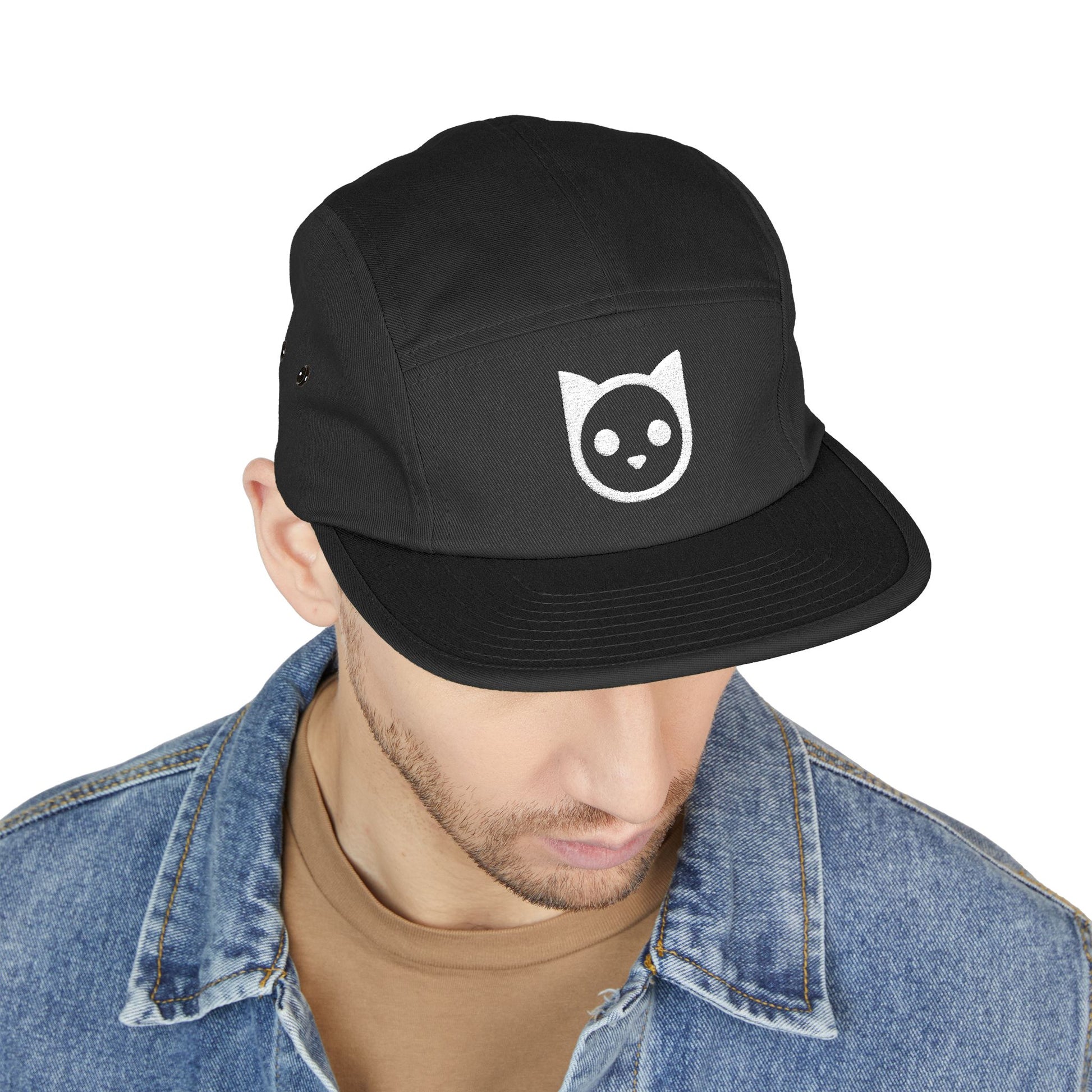 Black cap with a white cat icon worn by a person on a white background. Minimal embroidered cat icon design on 5-panel cap. TEEZOCA