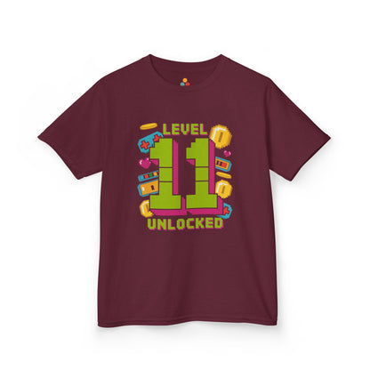 Dark green kids’ t‑shirt with neon green pixel “11” surrounded by gaming icons and “Level 11 Unlocked” text, flat front view.
