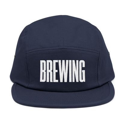 Navy blue cap with 'BREWING' text on a white background. BREWING minimalist text embroidery design on 5-panel cap. TEEZOCA