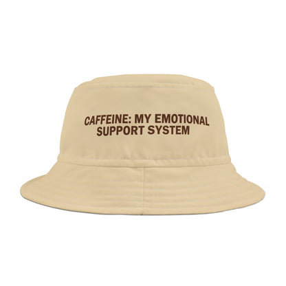 Beige bucket hat with funny text 'CAFFEINE: MY EMOTIONAL SUPPORT SYSTEM' on a white background. TEEZOCA