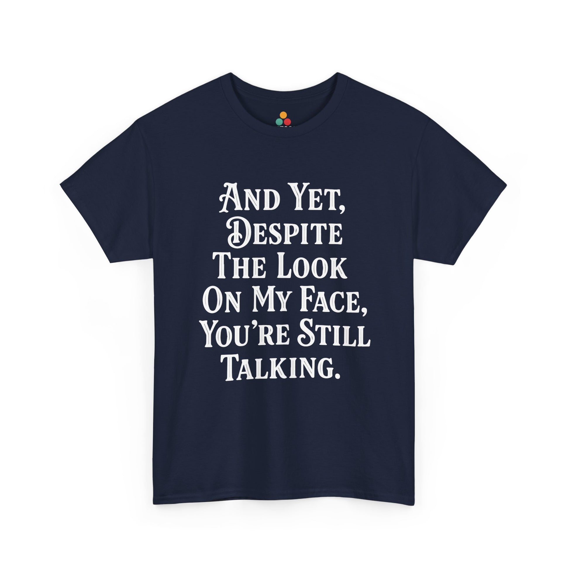 “Teezoca And Yet Despite the Look on My Face You’re Still Talking t-shirt, minimalist sarcasm typography, navy blue tee, front view.”

