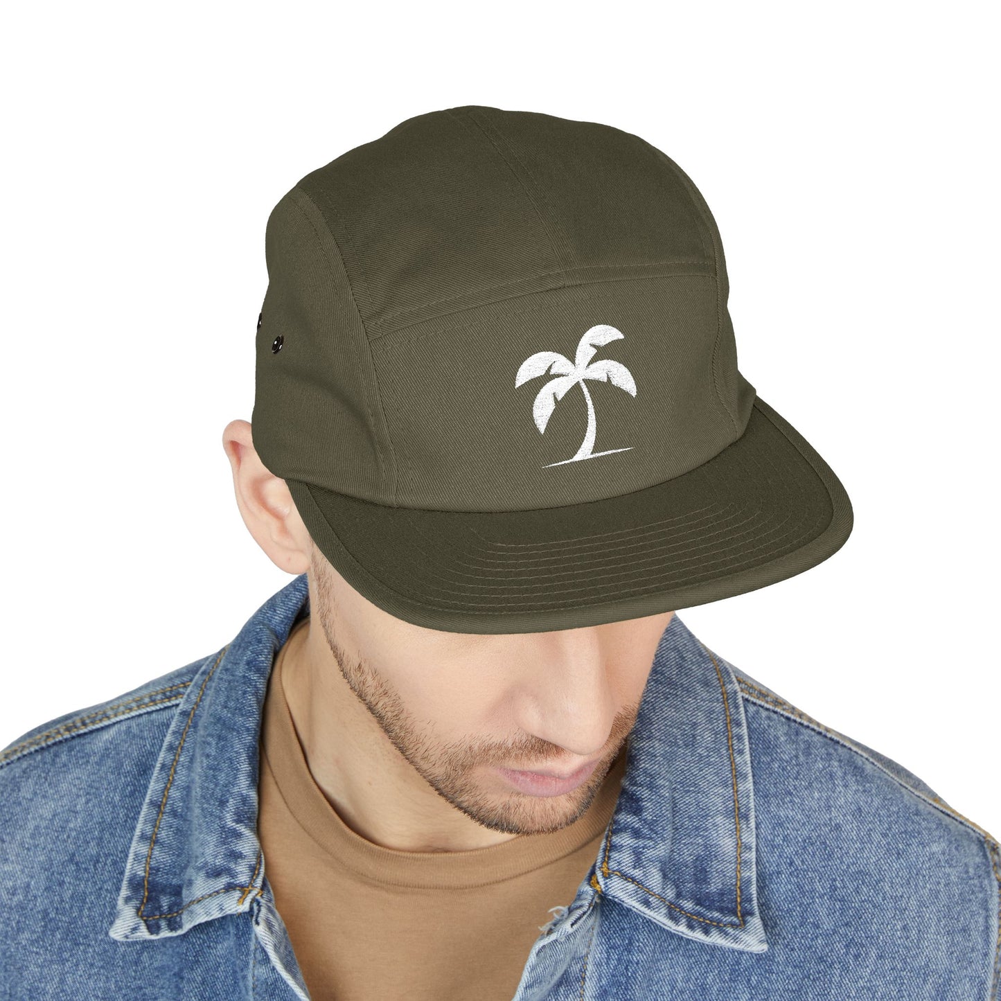 Green cap with palm tree design worn by a person on a white background. Minimal palm tree silhouette embroidery design on 5-panel cap. TEEZOCA
