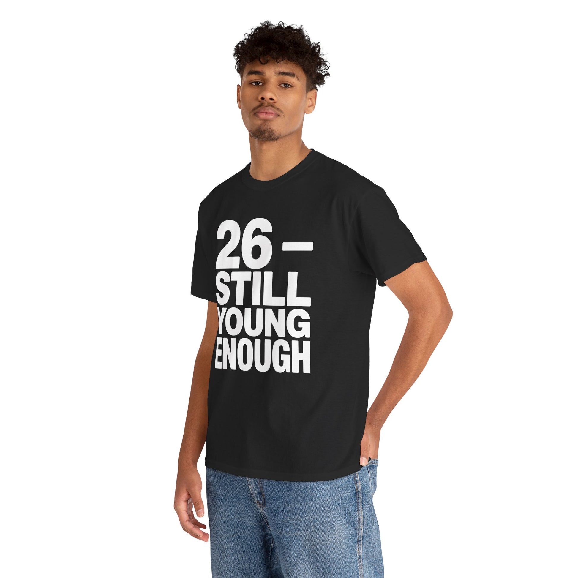 Person wearing a black t-shirt with '26 - STILL YOUNG ENOUGH' text on a white background